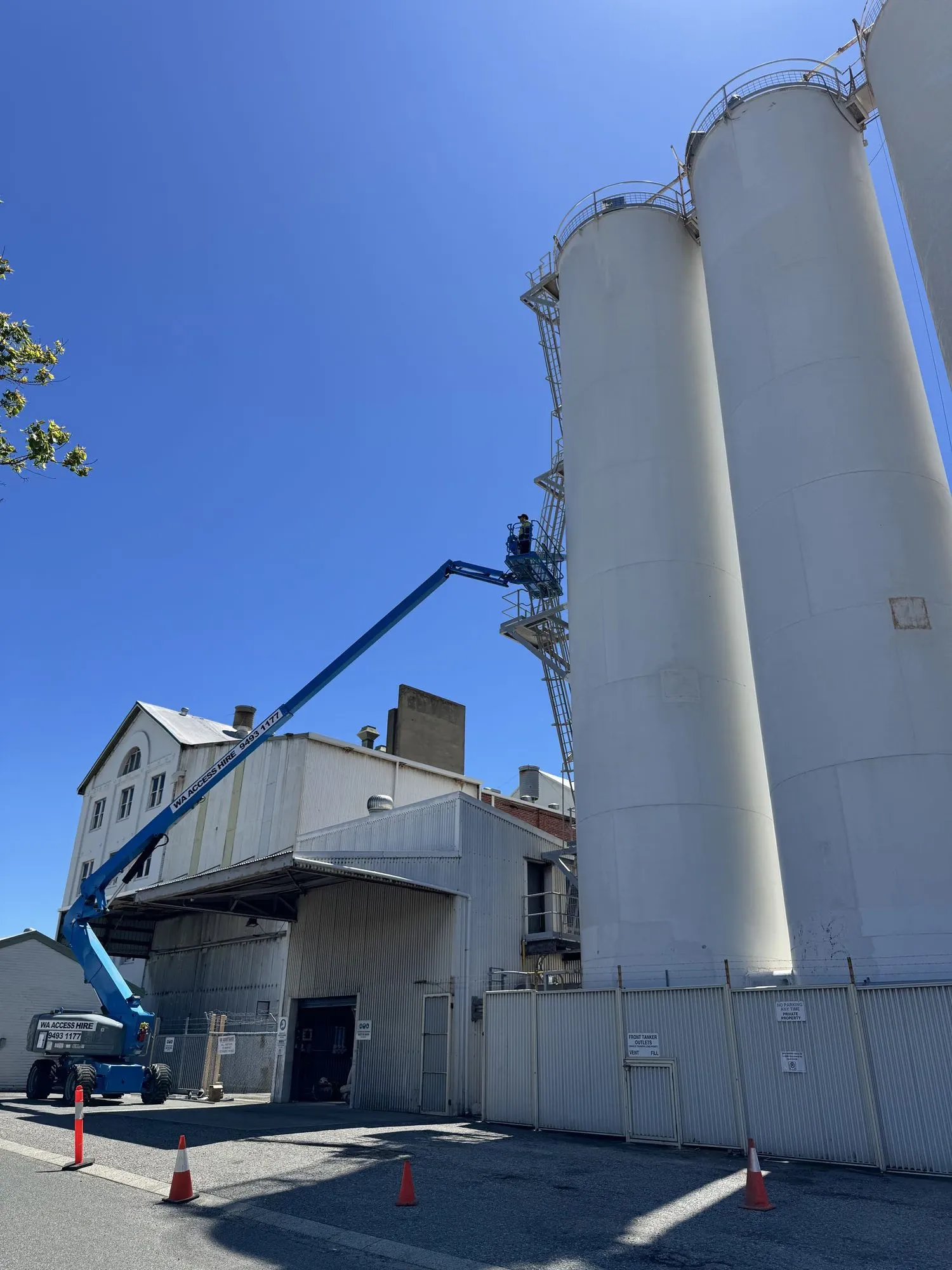 Boom lift raised alongside tall white flour mill silos during a bulk outloading upgrade