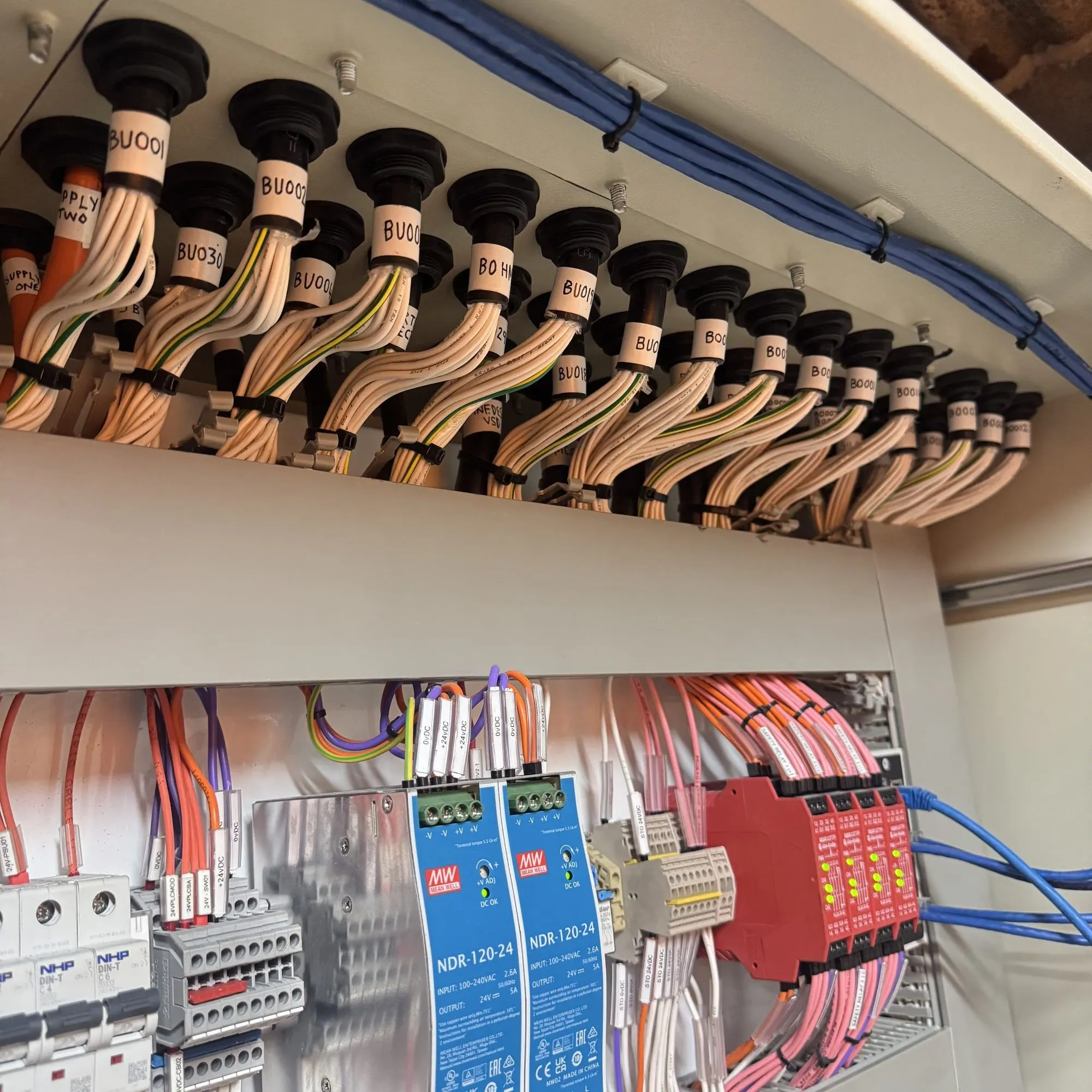 Panel interior with 24 V power supplies, safety relays, miniature circuit breakers and labelled cable entries