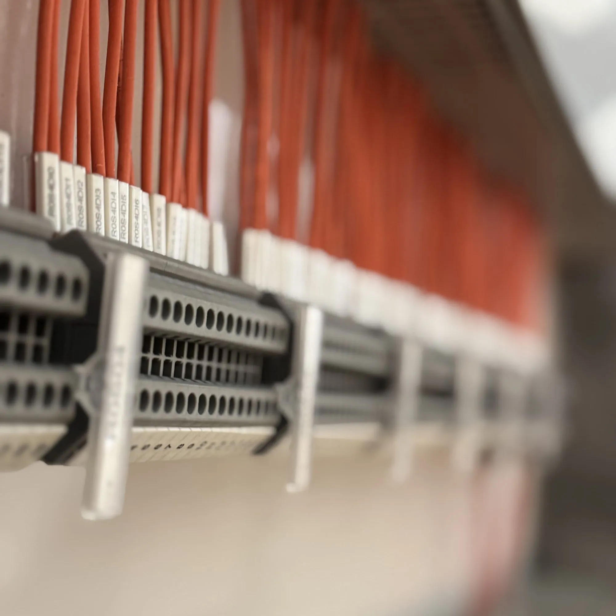 Close-up of ferruled orange control wiring with printed markers landed on panel terminal rails