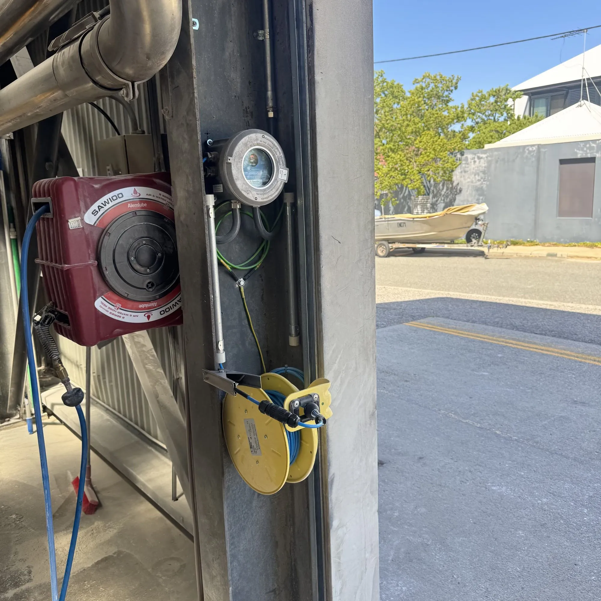 Hose reel, retractable lead reel and a weatherproof fitting mounted at an outdoor mill wash-down point