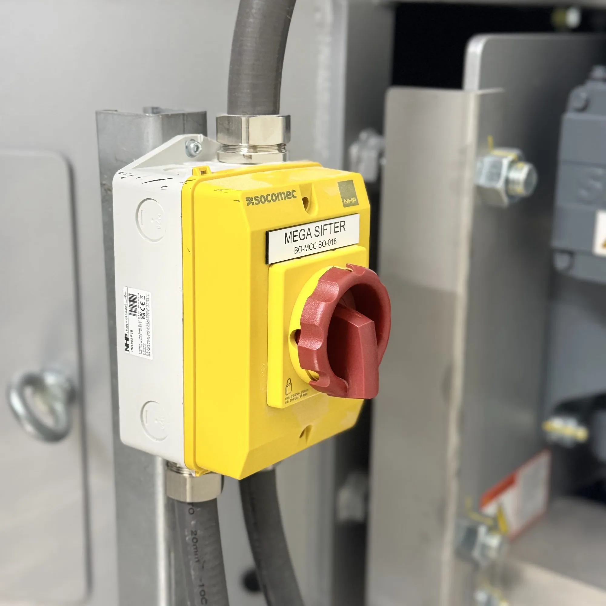 Yellow rotary isolator labelled Mega Sifter, mounted on galvanised strut beside a screened cable gland