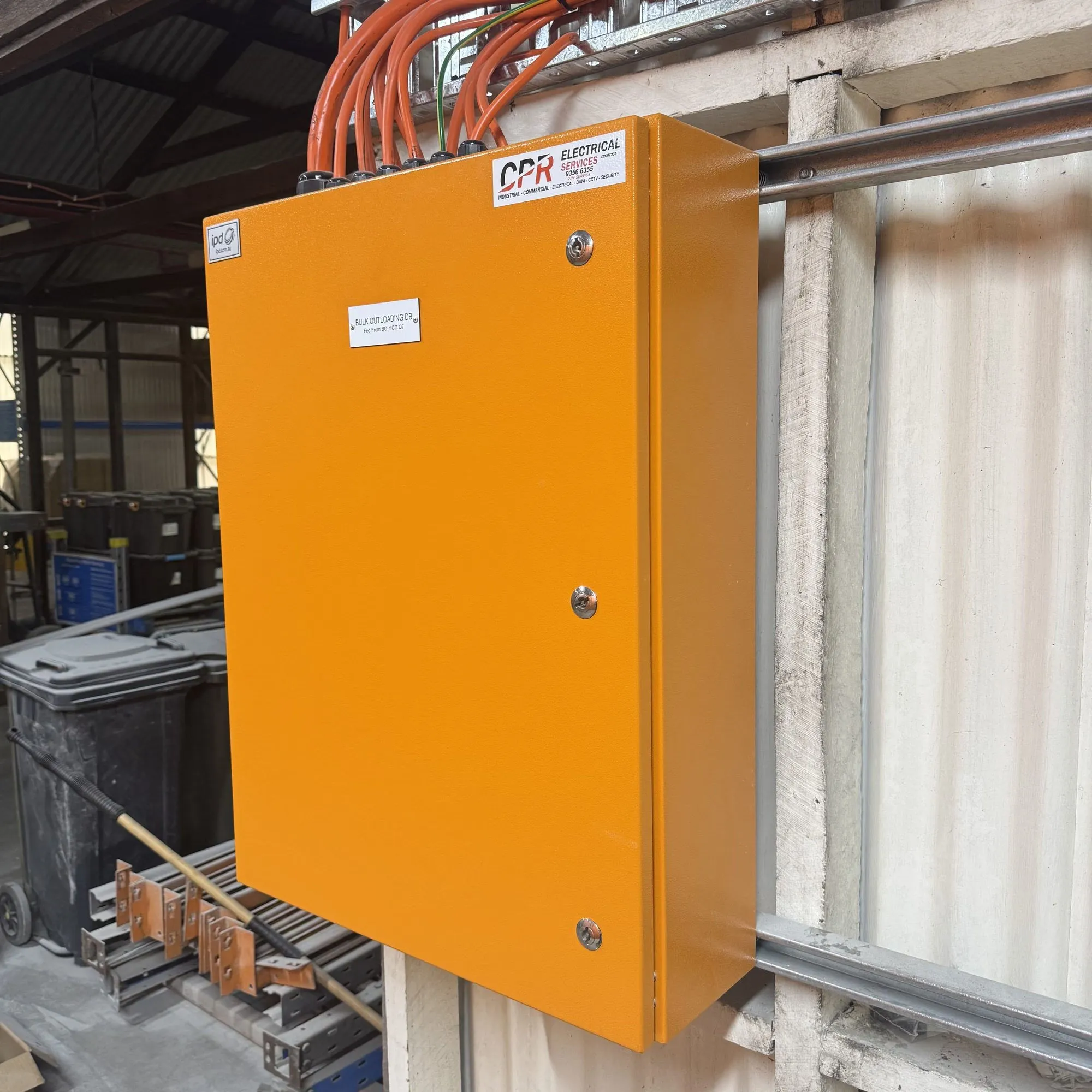 Orange wall-mounted enclosure carrying a CPR Electrical label, orange cables entering through top glands